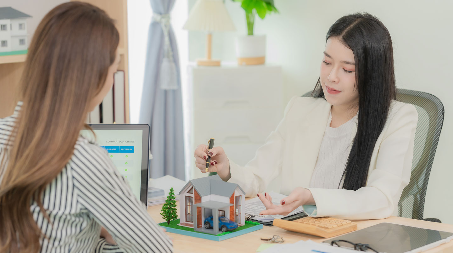 Consultant en agence immobilière présentant un dossier d'évaluation de bien avec documents sur table